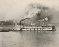 The riverboat "Valiant" passing Wheeling Wharf. Notice that her smokestacks are down so that she could clear the bridges.